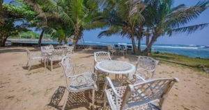 Beach terrace at the clubhouse of Aganthuka Galle, featuring three round tables each with four chairs, overlooking the private beach. This serene setting provides a perfect spot for relaxation and ocean views, located just a 5-minute drive from the main Aganthuka Galle complex.